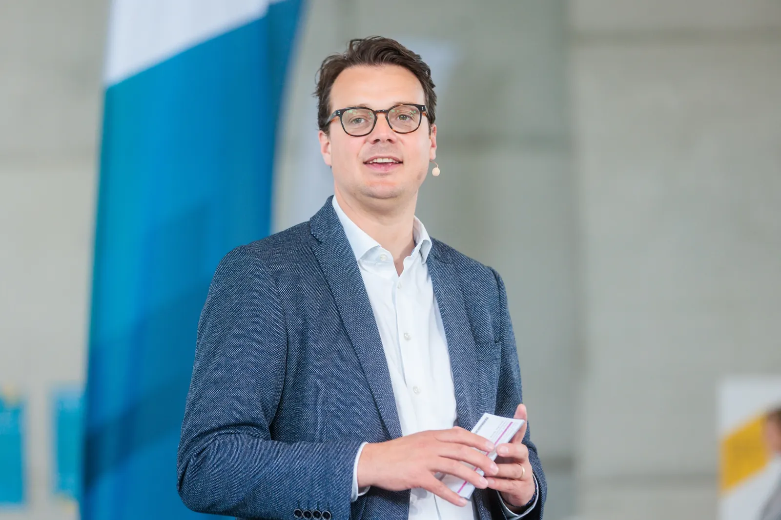 Jens Issel im blauen Sakko hält Karteikarten und spricht