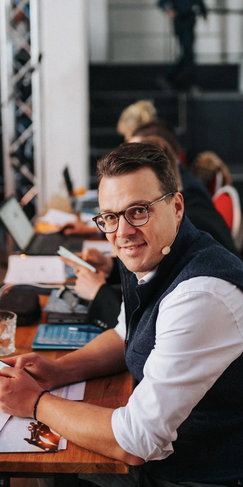 Jens Issel mit Headset lächelt am Moderationstisch in die Kamera