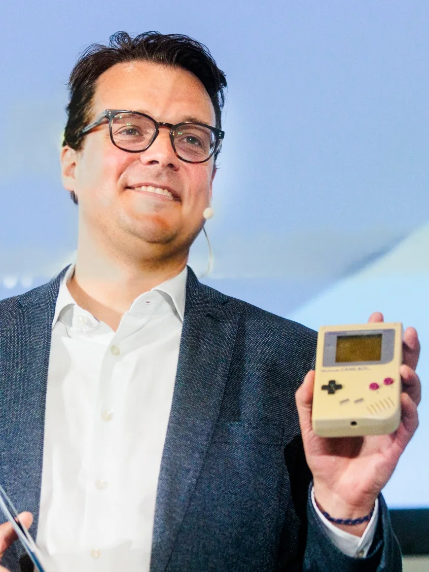 Jens Issel lächelt und hält einen alten Gameboy in die Höhe