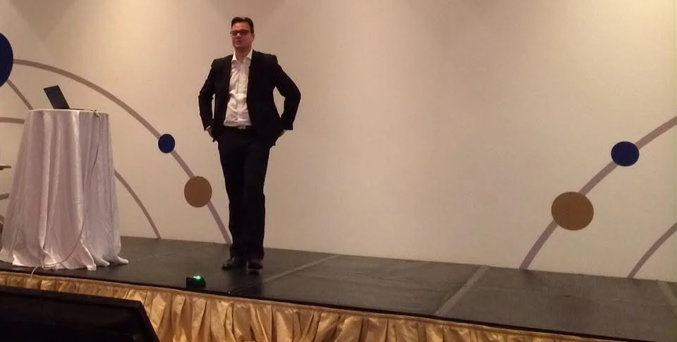 Jens Issel steht mit den Händen in den Taschen auf einer Bühne in einem Ballsaal, Keynote 2014 am Toten Meer in Jordanien